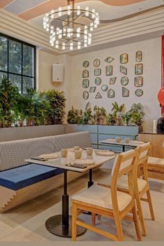 an empty restaurant with tables and benches in front of large windows that have potted plants on them