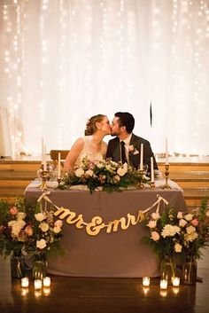 a couple kissing in front of a table with candles