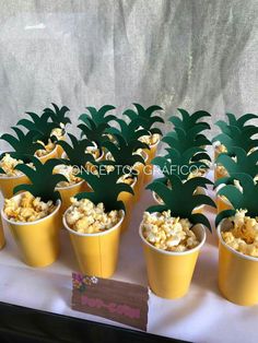 small yellow pots filled with popcorn and pineapple cut out on top of each other