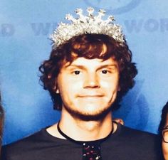 a man wearing a tiara standing next to two women