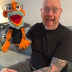 a man sitting on top of a couch with a stuffed animal in front of him