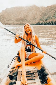 a woman sitting on top of a kayak in the water