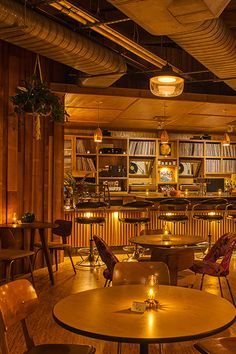 the interior of a restaurant with wooden tables, chairs and bookshelves on the walls