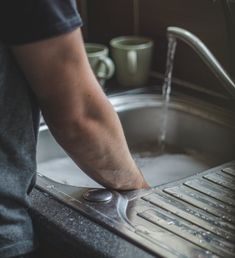 a man is washing his hands in the kitchen sink with water running from the faucet