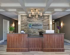 the front desk of a hotel lobby with stone wall and wood paneled reception counter