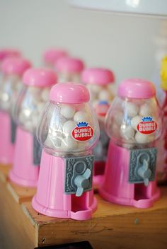 there are many gummy machines on the table with balls in them and one is pink