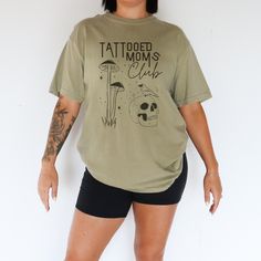 💀 Join the Fiercest Club Around--Tattooed Moms Club! 💀 Are you a proud, inked-up mama with a rebellious spirit? This "Tattooed Moms Club" oversized t-shirt is just for you! With a bold skull and mushroom design, this tee is for the moms who rock tattoos, raise awesome kids, and live life on their own terms. Whether you're juggling school drop-offs or crushing it at work, this shirt shows the world that tattooed moms are a league of their own--fierce, fun, and unapologetic. 🍄 Why You'll LOVE T Tattooed Mom Shirt, Mother Of Dragons Shirt Mom, Rock Tattoos, Overstimulated Moms Club Shirt, Mother Of Dragons Shirt, Skull Mushroom, Tattoo Mom, Mushroom Graphic, Club Tshirt