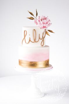 a three tiered cake with pink flowers on top and gold lettering that says lilly