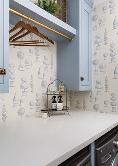 a laundry room with blue cabinets and wallpaper that has boats on it, hanging from the ceiling