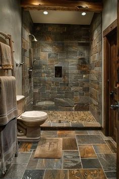 a very nice looking bathroom with stone flooring and tile on the shower stall wall