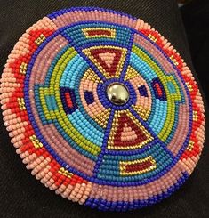 a colorful beaded brooch sitting on top of a black surface