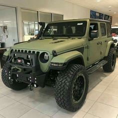 a green jeep is parked in a showroom