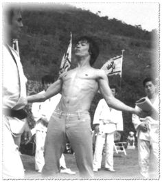 black and white photograph of man with no shirt holding american flag in front of other men