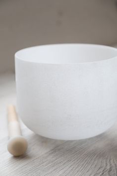 a large white bowl sitting on top of a wooden table next to a rolling pin