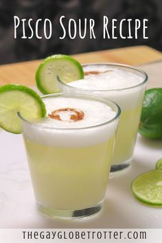 two glasses filled with drinks sitting on top of a table next to limes and an orange