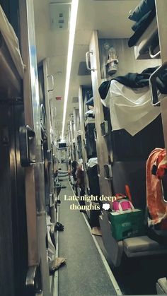 an empty train car with lots of luggage on the floor and people walking down it