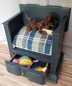 a brown dog laying on top of a bed in a blue wooden toy box with drawers