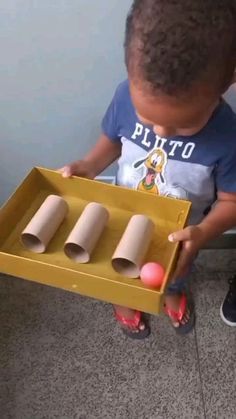 a little boy playing with some toys in a box on the floor and looking at it