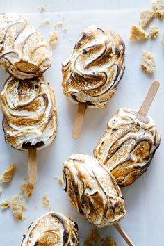 marshmallows are sitting on top of a sheet of parchment paper and have been drizzled with icing