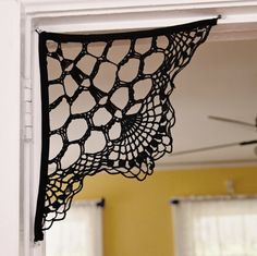 a black doily hanging off the side of a window in a room with yellow walls