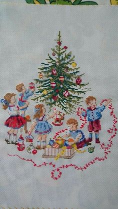 a cross stitch christmas tree with children around it