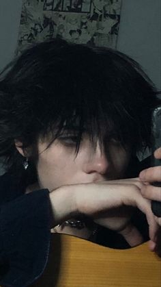 a person with black hair holding a cell phone to their face and looking at the camera