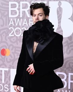 a male in a black suit and bow tie on the red carpet at an awards event