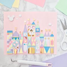 a paper cut out of a castle on top of a table next to some scissors