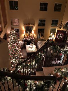 a christmas tree is lit up on the stairs in this living room with other decorations