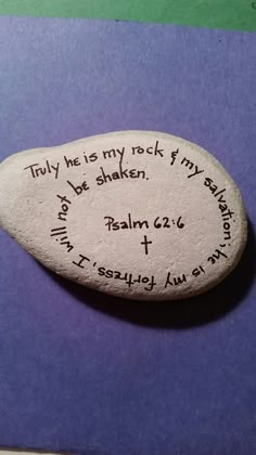 a rock with writing on it sitting on top of a purple table next to a pen