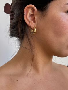 a close up of a person with tattoos on her back and ear piercings in gold