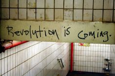 a sign that reads revolution is coming above a urinal