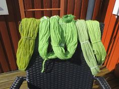 four skeins of yarn sitting on top of a black chair next to a wooden fence