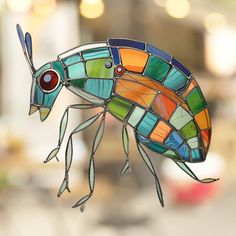 a stained glass insect with red eyes on it's body