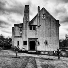 a black and white photo of an old building with two people standing in front of it