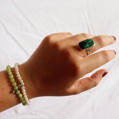 The vibrant green malachite stone sits in a sterling silver case and band to create this unique ring. An array of green tones and shades can be found in the rectangle cut of the natural malachite stone. Due to the natural components in the malachite stone each stone is perfectly unique.   Available in three sizes: US ring size 8, 9, & 10. Match with your choice of malachite jewelry from our La Stele collection. Store in a safe place to avoid scratching. Clean carefully with a jewelry polishing c Elegant Green Chrysocolla Jewelry, Green Emerald Rings With Natural Stones, Green Emerald Ring With Natural Stones, Green Rectangular Sterling Silver Jewelry, Minimalist Adjustable Green Emerald Ring, Green Emerald Rectangular Stone Jewelry, Green Rectangular Jewelry With Natural Stones, Green Malachite Rings As A Gift, Rectangular Green Gemstone Jewelry