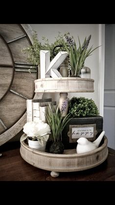 a wooden shelf filled with plants and knick knacks on top of a table