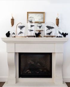 a mantle with candles and bats on it in front of a mirror above the fireplace