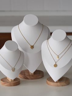 three white mannequins with gold necklaces on them