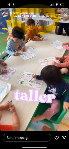 children are sitting at a table with their hands on paper