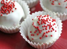 white chocolates with red sprinkles are sitting on a red tablecloth