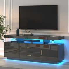 an entertainment center with a large television mounted on it's wall and illuminated shelves