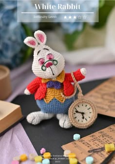 a crocheted white rabbit holding a clock on top of a black table cloth