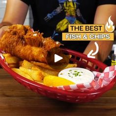 fish and chips in a basket on a table with a person sitting at the counter behind it