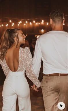 a man and woman holding hands while standing next to each other on a dance floor