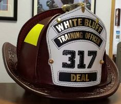 a fireman's hat sitting on top of a desk in front of pictures