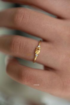 a woman's hand with a yellow and white diamond ring on top of it