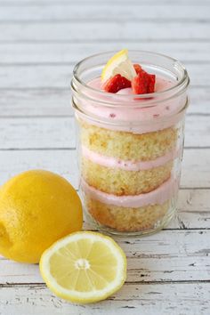 a lemon and strawberry cake in a jar next to a sliced lemon