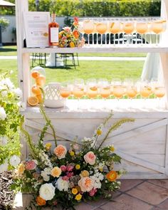 an outdoor bar with flowers and lemons on it's display shelf for drinks