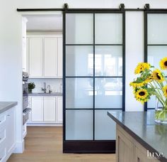 a vase with sunflowers in it sitting on a kitchen counter next to a sliding glass door